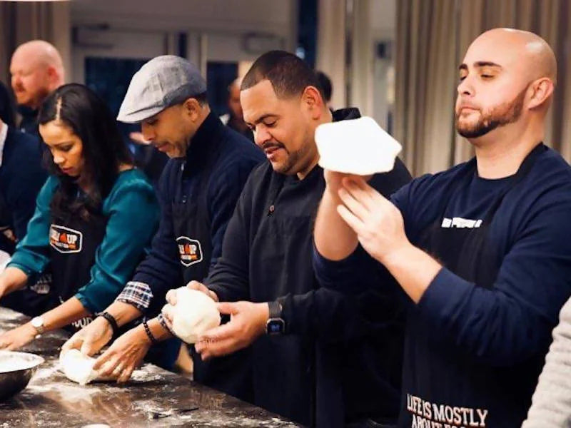 Man tossing pizza dough during Selfup cooking class